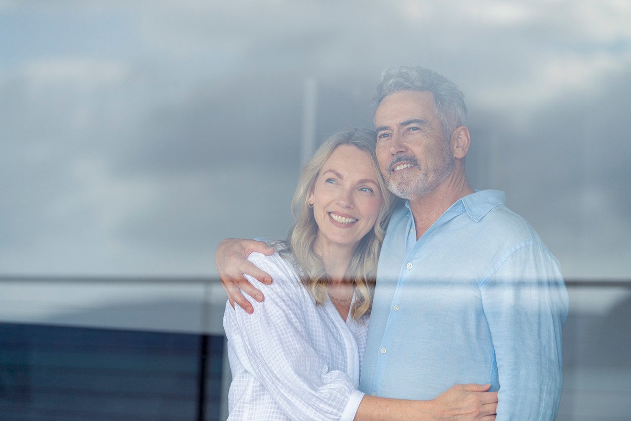 Couple heureux regardant par la fenêtre 
