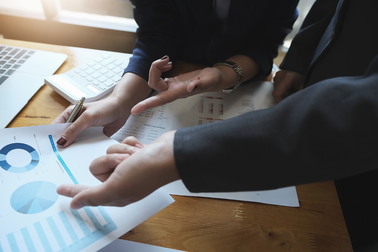 Plusieurs mains pointant des feuilles de présentation sur un bureau