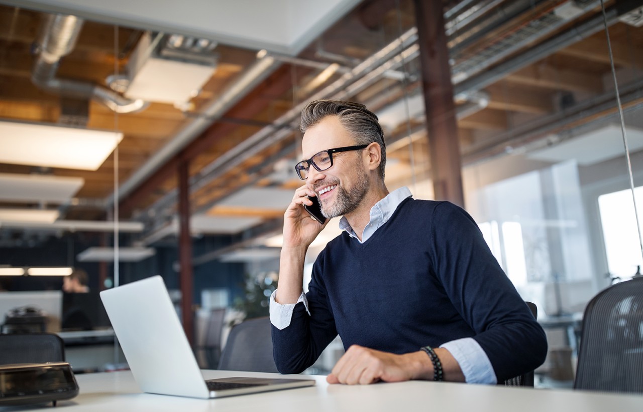 Man talking on the phone and looking at his computer in an office