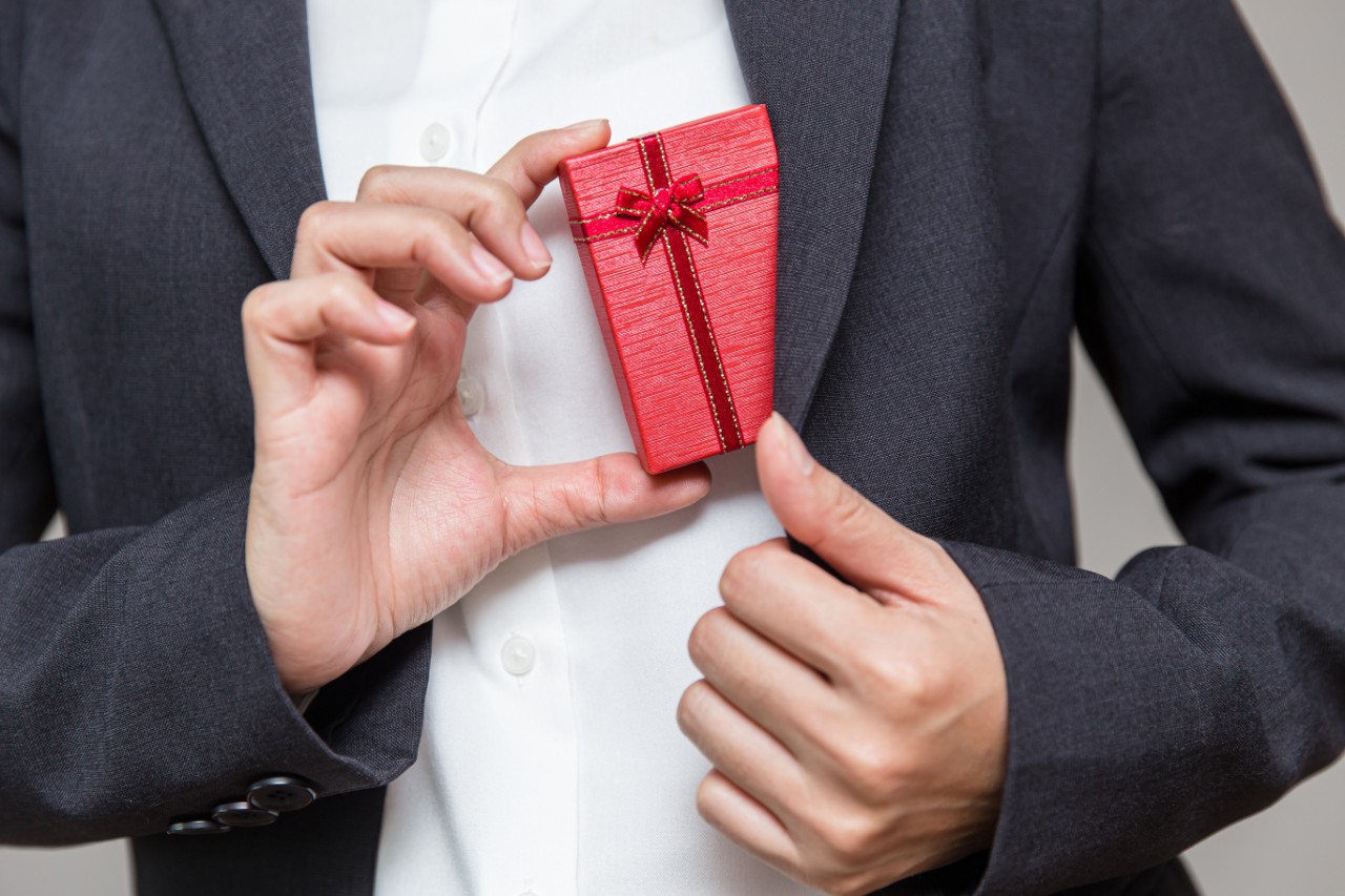 Businessman pulls a gift box out of his suit