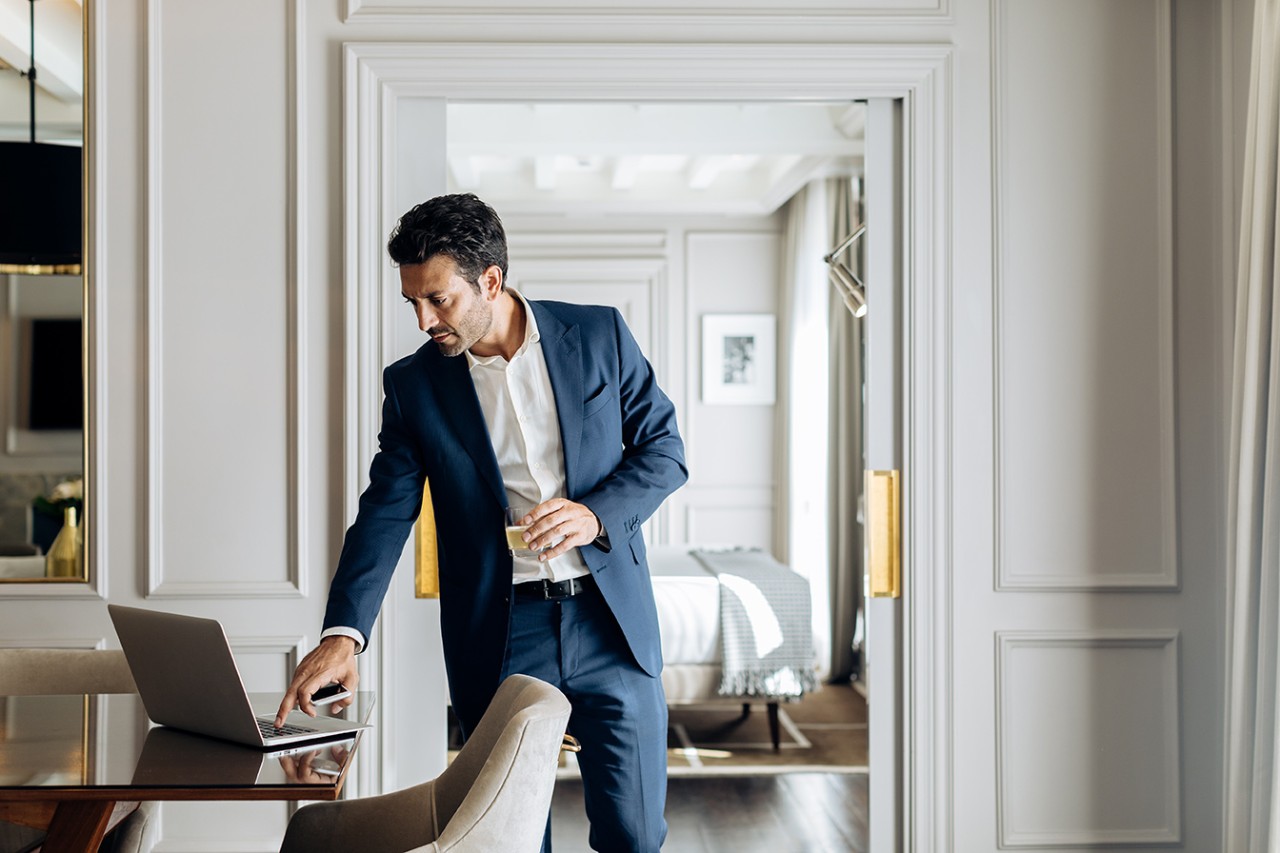 Un monsieur en costume dans un appartement regardant son ordinateur